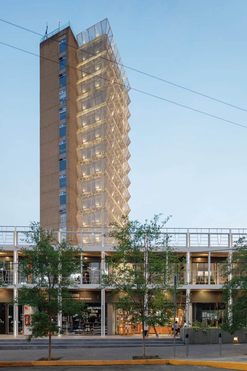 Torre corporativa de oficinas SIGOB® al atardecer, edificio en forma de L con fachada de celosía dorada